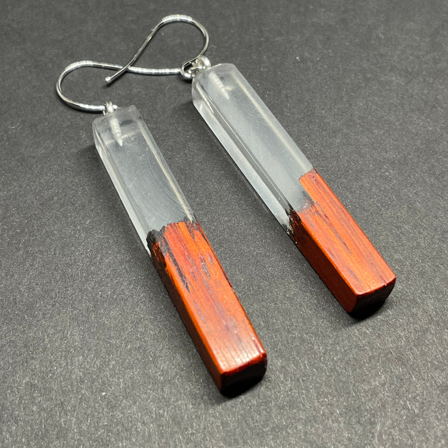 Earrings handmade with clear resin and live edge, burnt African padauk wood, shaped in straight plank stems.