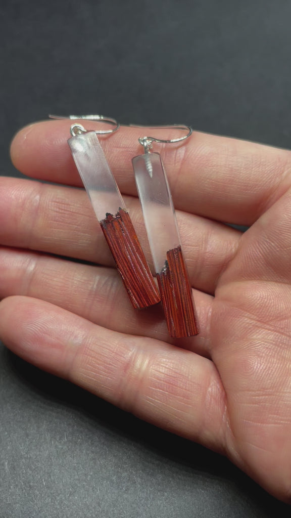 Earrings handmade with clear resin and live edge, burnt African padauk wood, shaped in straight plank stems.